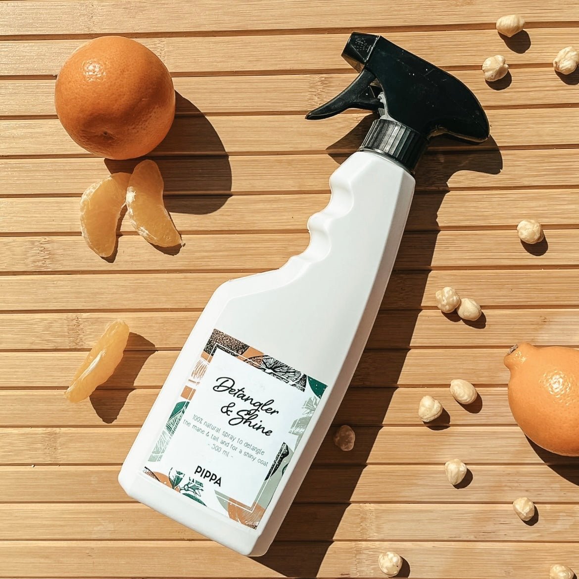 pippa detangler shine spray fles liggend op tafel met de ingredienten 
