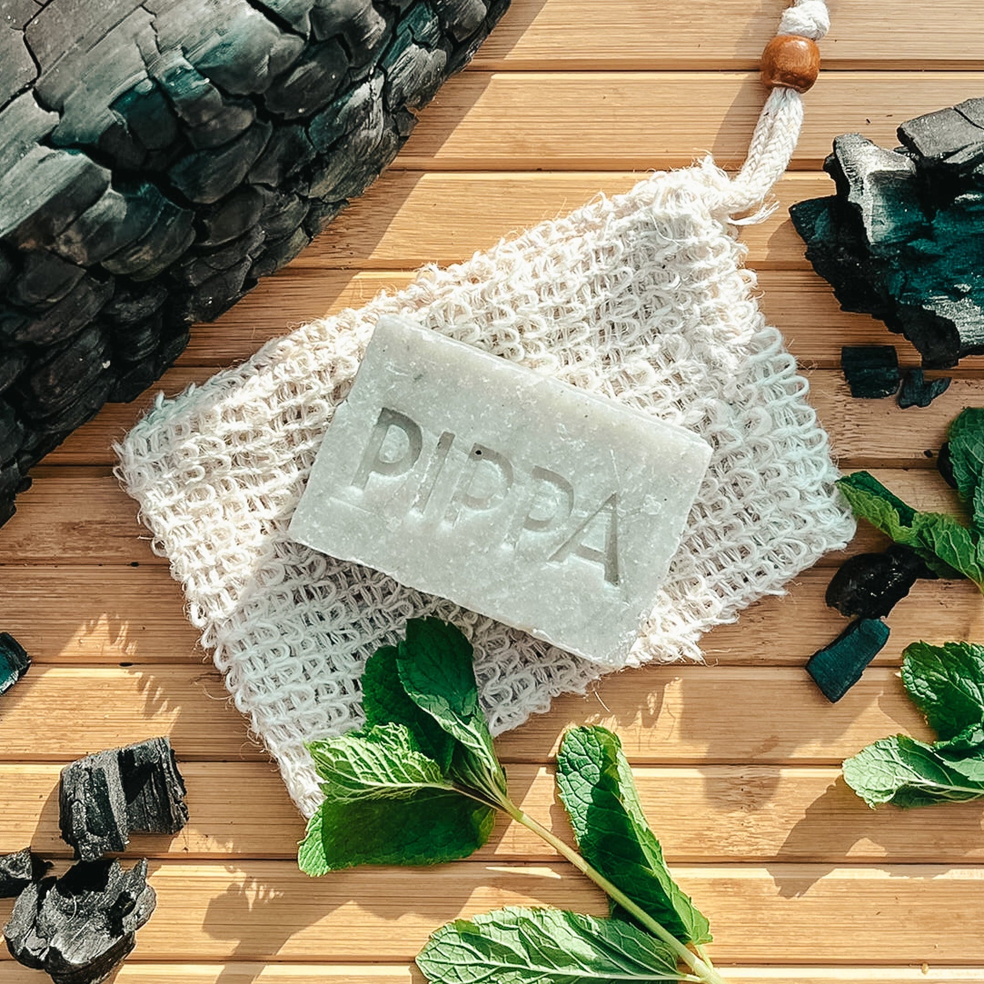 pippa hondenshampoo charcoal en peppermint shampoobar met sisal zeepzakje en de ingredienten ligt op tafel