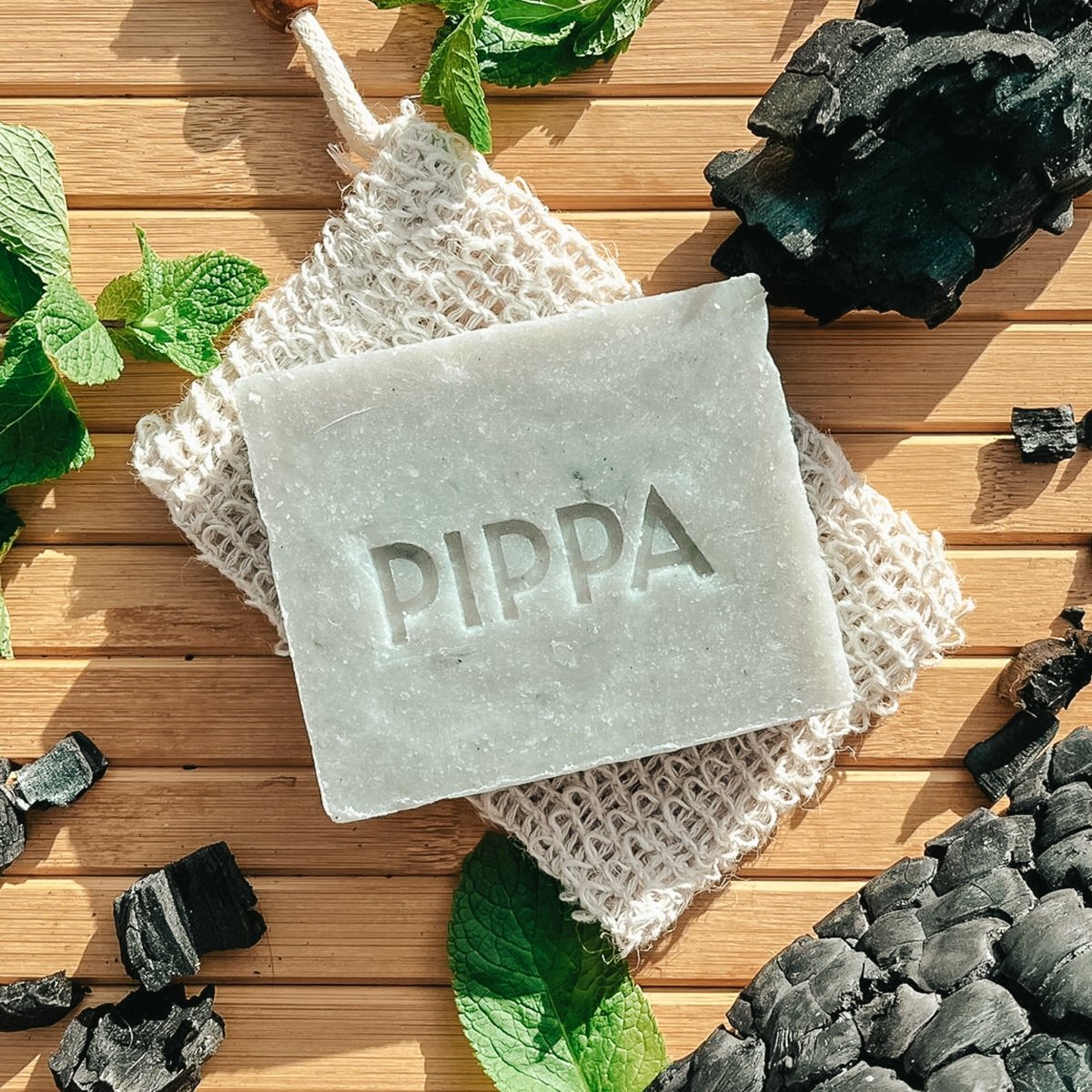 pippa paardenshampoo charcoal en peppermint shampoo bar ligt op tafel met de ingredienten en het sisal zeepzakje