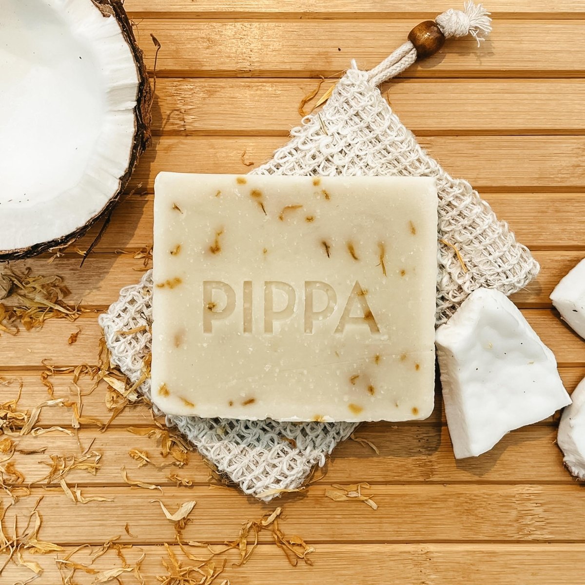pippa paardenshampoo coconut en marigold shampoobar op het sisal zeepzakje op tafel met een kokosnoot